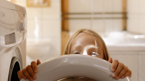 Niña frente a una lavadora: reduce los gastos de energía