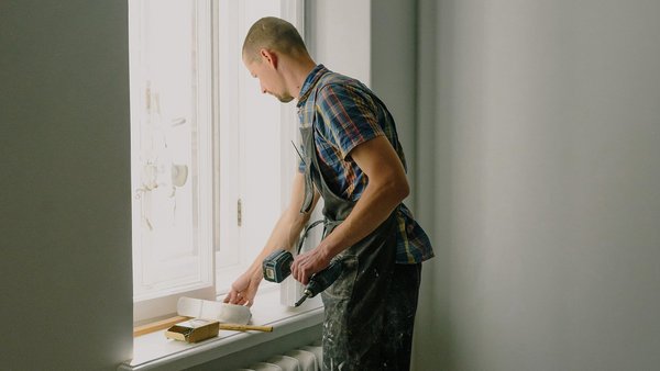 Un hombre repara una ventana - seguro de incapacidad laboral privado Un hombre repara una ventana - seguro de incapacidad laboral privado