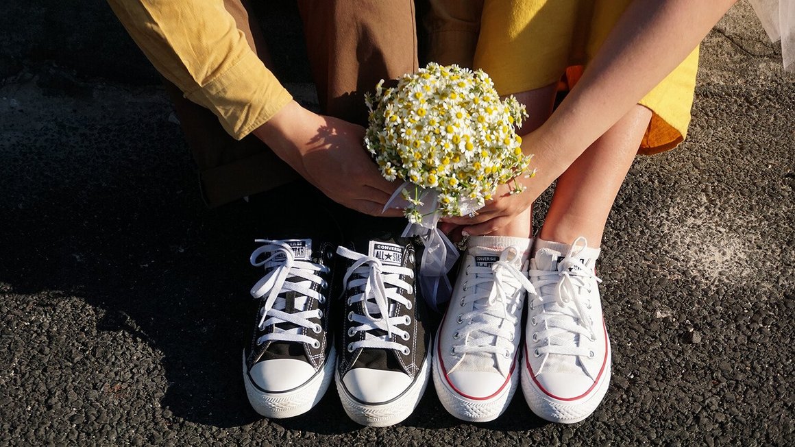 Pareja sentada en el suelo con flores en la mano - Wedding Planning