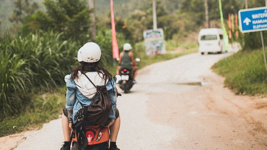 Mujer joven en un scooter - mochileo en el extranjero