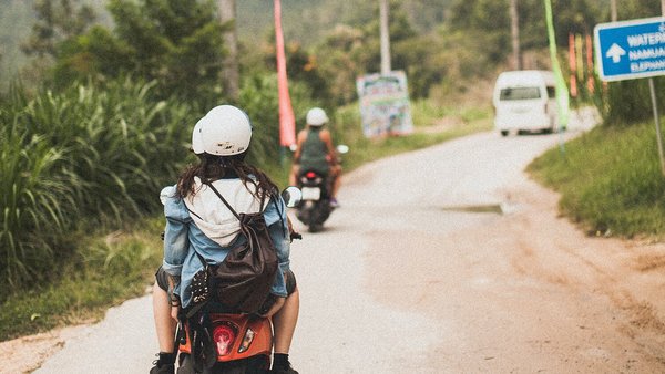 Mujer joven en un scooter - mochileo en el extranjero Mujer joven en un scooter - mochileo en el extranjero