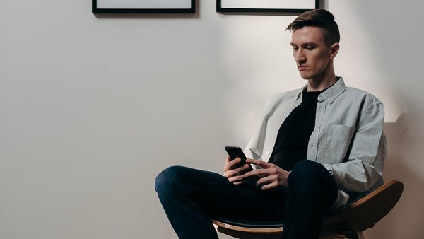 Hombre mira ansiosamente su teléfono móvil - aumento de precios Hombre mira ansiosamente su teléfono móvil - aumento de precios
