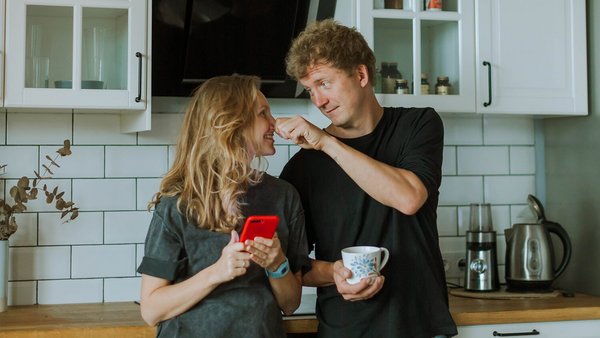 Mujer y hombre de pie riendo en la cocina – cuenta conjunta Mujer y hombre de pie riendo en la cocina – cuenta conjunta