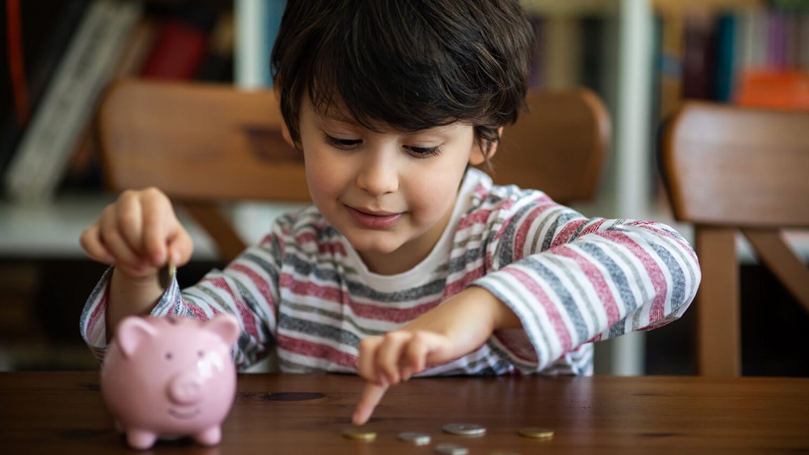 Niño con hucha y monedas – costes fijos en el hogar