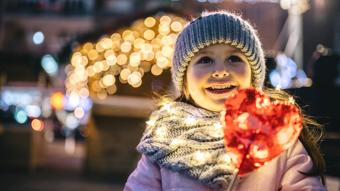 Niña con corazón y luces navideñas – Invertir con éxito 