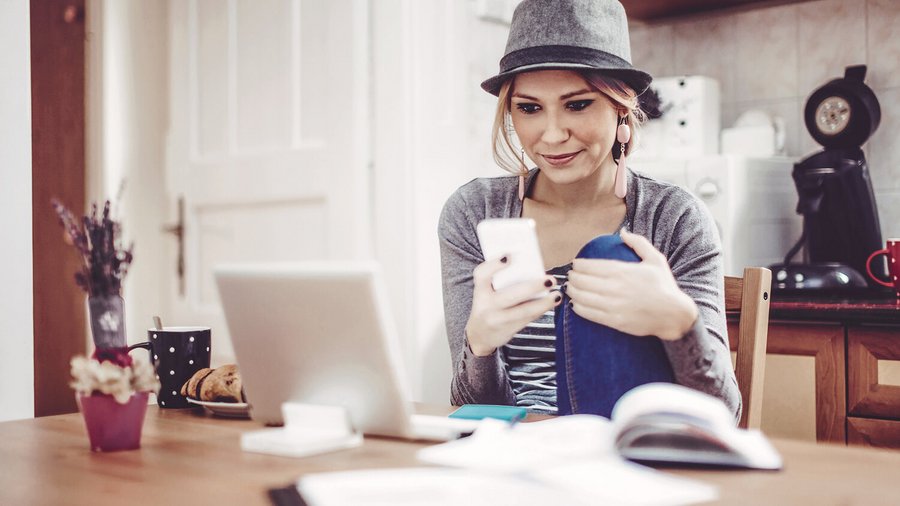 Joven en la mesa con un smartphone, un cuaderno y documentos para llevar el libro de cuentas del hogar.