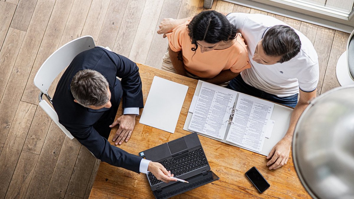 Pareja joven con el consultor financiero de OVB en la mesa