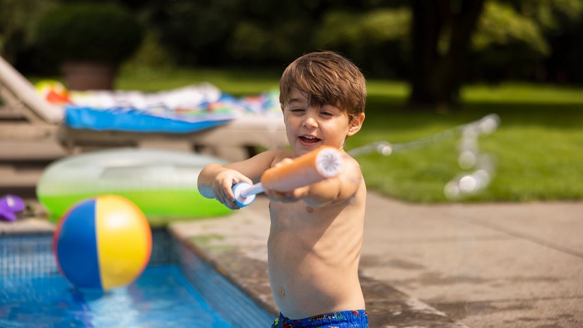Niño en la piscina con una pistola de agua – Viaja con tranquilidad