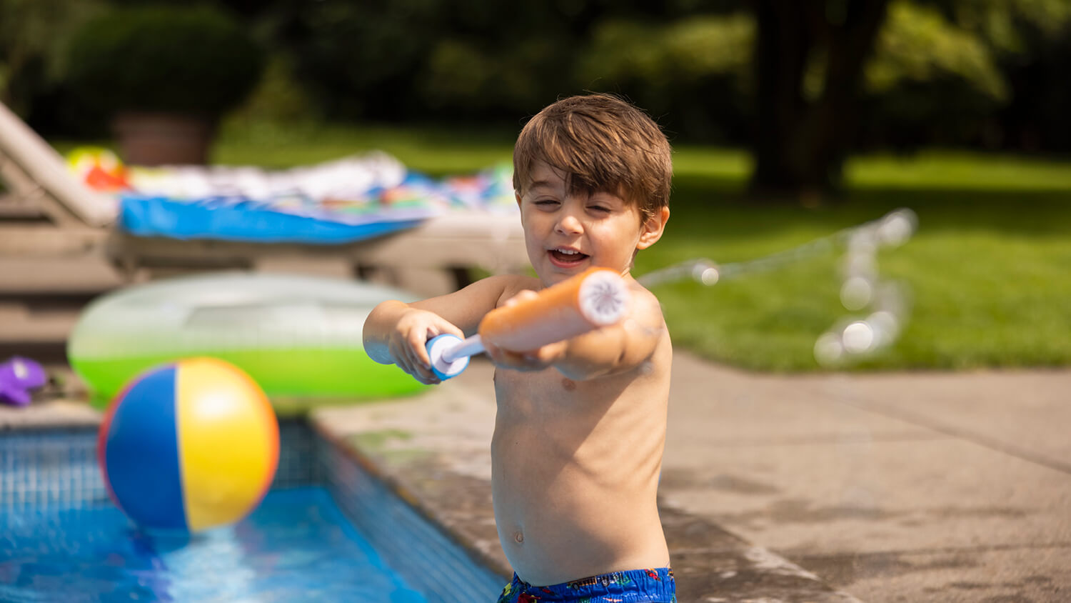 Niño en la piscina con una pistola de agua – Viaja con tranquilidad Niño en la piscina con una pistola de agua – Viaja con tranquilidad